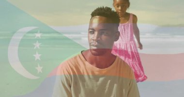 Kızının kumsalda babasına doğru koşması, açık bayrak altında sağlığını göstermesi. Aile, açık hava, kıyı, doğa, sevecen, bağ kurma, boş zaman