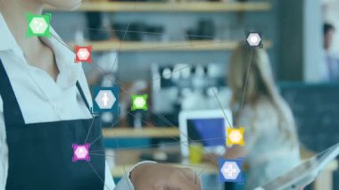 Barista tableti tıklatıyor ve kafedeki gövde çerçeveli yüzey üzerinde yüzen altıgen veri simgelerini etkinleştiriyor. Teknoloji, dijital, iletişim, ağ, yenilik, modern, gelişigüzel