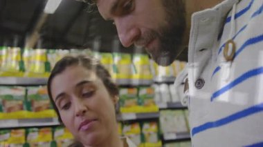 Sağlık istatistiklerini gösteren veri grafikleriyle koridorda yağ şişesini tarayan çift. Romantizm, alışveriş, tüketim, sağlık, analiz, market, yaşam tarzı