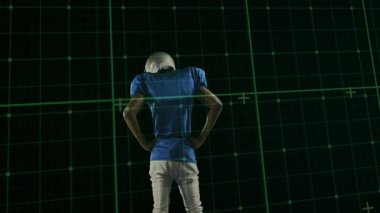 Futbolcu spor teknolojisinde tarama için bekliyor, kafasını kaldırıyor ve yeşil şebekeye karşı miğferi çeviriyor. Sporcu, spor, ızgara, dijital, teknoloji, performans, eğitim