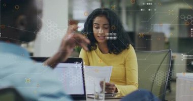 Sarı bluzlu bir iş kadını, dijital kaplamalı bir dosyayla yüksek sesle kitap okuyor. İşbirliği, iletişim, profesyonellik, modern, takım çalışması, odaklanma, üretkenlik