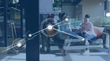 İş ofisindeki tablet üzerinde çalışan kadınlar, akış gösteren animasyon ağlarını başlatan düğümle birlikte. İşbirliği, takım çalışması, yenilik, dijital bağlantı, modern çalışma alanı, profesyonel büyüme, yaratıcı ortam