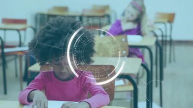 Dijital dairesel arayüz sınıfta kaybolurken ve odak noktasını yönlendirirken öğrenci kağıda yazı yazıyor. Teknoloji, eğitim, öğrenme, yenilik, odaklanma, konsantrasyon, sınıf