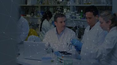 Laboratuvar bilim adamı dizüstü bilgisayarı ayarlıyor ve işaret ediyor. Ekip, ağ kaplamalı mikro plaka kullanıyor. Araştırma, yenilik, işbirliği, bilim, teknoloji, analiz, modern