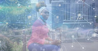 Yüz maskeli Afrikalı Amerikalı bir kadının veri işleme görüntüsü. Küresel iş ve dijital arayüz kavramı dijital olarak oluşturulmuş görüntü.