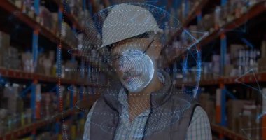 Depo çalışanı, depo koridorunda holografik dünya taraması yaparken yüzünü kaldırıyor. Gelecekçi, teknoloji, lojistik, yenilik, analiz, güvenlik, sanayi