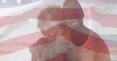 Erkek, güneşli plajda kadına sarılıyor, bayrak grafiği soluyor ve vatansever pazarlama için dalgalanıyor. Romantizm, kutlama, vatanseverlik, açık hava, sükunet, sevgi, neşe