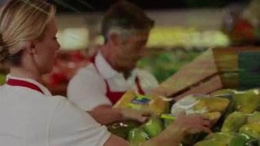 Orta kadın perakende satış elemanı, yeşil kod geçişi olarak muz tepsisini döndürüyor ve yoğunlaşıyor. Perakende, market, takım çalışması, otomasyon, teknoloji, üretkenlik, tazelik