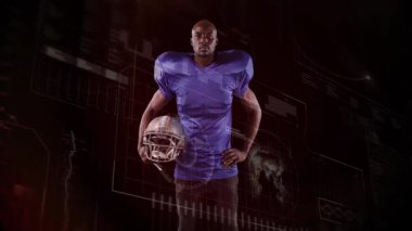 Karanlık stüdyoda kask tutan futbolcu kamera performans grafiklerini gösterirken. Sporcu, yenilik, fütüristik, teknoloji, spor, analitik, rekabet