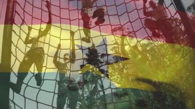 Üç erkek takım arkadaşı halat ağını tutuyor, Ghanaian bayrağının altında yukarı doğru çekiyorlar ve formda olduklarını gösteriyorlar. Macera, takım çalışması, mücadele, azim, açık hava, fitness, esneklik