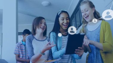 Genç kızlar okulda tablet dinlerken, erkekler telefonları kaydırıyor, ağ simgeleri grup etrafında genişliyor. İşbirliği, bağlantı, teknoloji, gençlik, eğitim, yenilik, sosyal