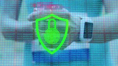 Kalkan simgesini gösteren ve sosyal medya bağlantısını takip eden bir kadın bilek dinleme cihazını masada kaldırıyor. Siber güvenlik, dijital arayüz, teknoloji, veri analizi, yenilik, uzaktan çalışma, gelecekçi