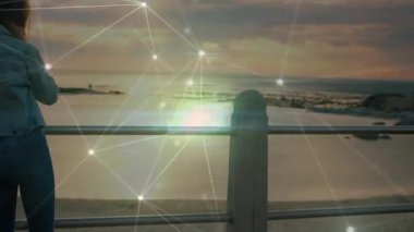 Akıllı telefonu kaldıran kadın, arama yapıyor ve ufukta tarama yaparken teknoloji ağını etkinleştiriyor. Kadınsı, tefekkür, alacakaranlık, bağlantı, açık hava, manzara, huzur