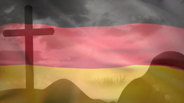 Alman bayrağı çimenli tepelerin üzerinde esintiye yakalanıyor. Dalgalanan kıvrımlar ciddi bir ruh hali uyandırıyor. Sembol, vatanseverlik, manzara, hareket, siluet, kumaş, anıt