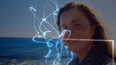 Sahilde duran bir kadın, mavi enerji hattı beliriyor, yüz boyunca zikzak çiziyor, teknoloji görüntüsü yaratıyor. Fütürist, soyut, dinginlik, keşif, yenilik, dijital, doğal