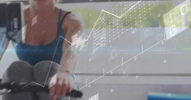 Kürek çeken iki kadın, spor salonunda veri grafikleri çiziyor ve senkronize vuruşlar yapıyor. Fitness, egzersiz, dijital, performans, takım çalışması, motivasyon, modern