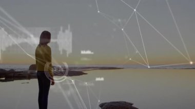 Alacakaranlık 'ta kayaya basan kadın atımlı HUD düğümleri haritalama ufkuyla teknolojik ağ örtüsü fırlatıyor. Gelecek, yenilik, bağlantı, dijital, bilim, teknoloji, manzara