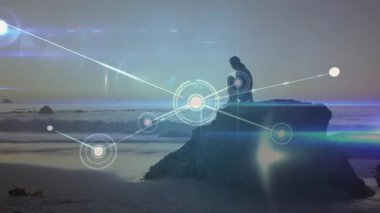 Kaya üzerinde oturan bir kadın holografik teknoloji ağını tetikliyor ve etrafını kavrayabilmek için genişliyor. Deniz manzarası, sükunet, fütüristik, dijital, yenilik, tefekkür, sanat