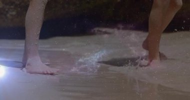 Kardeşler, seyyar pazarlama görselleri için kum üzerinde bacaklarını kaydırarak geri çekilen dalgalara tepki veriyorlar. Sahil, sahil, su, dalgalanma, su sıçratma, yalınayak, yaz