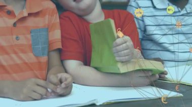 Kırmızı gömlekli çocuk yeşil kitap okurken yaşıtları not tutarken, çalışma için sarı kitap yerleştiriyor. Eğitim, işbirliği, okur yazarlık, sınıf, öğrenme, takım çalışması, akademik