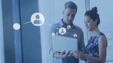 Dizüstü bilgisayar tutan adam ve raylara dokunan kadın ofisin üzerinde büyüyen bilişim ağı ikon hatlarını başlatıyorlar. Teknoloji, işbirliği, yenilik, bağlantı, dijital, modernite, takım çalışması