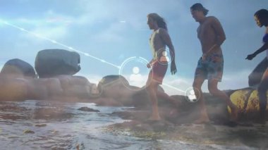 Arkadaşlar kıyı şeridi boyunca kullanıcı simgelerinin dijital ağ haritasını oluşturan gelgit havuzlarına ayaklarını daldırıyorlar. Sahil, bağlantı, teknoloji, açık hava, keşif, su, işbirliği