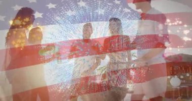 Izgarada kadeh kaldıran beş arkadaş, havai fişek grafikli şişe kaldıran kadın ve bayrak kaplayan yiyecek. Kutlama, açık hava, eğlence, yoldaşlık, gün batımı, yaz, sosyalleşme