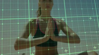 Yoga pratisyeni avuçlarına bastırıyor AR fitness taramasını başlatıyor, kumsalda yeşil ızgarada kollarını kaldırıyor. Meditasyon, farkındalık, maneviyat, dinginlik, açık hava, sağlık, teknoloji