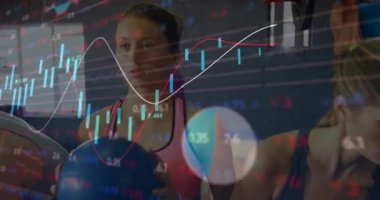 Başroldeki kadın, sağlık topunu hareket ettiriyor. Finans tablosu, partnerin dambıl kıvırırken aynı anda örtülüyor. Fitness, egzersiz, güç, işbirliği, motivasyon, sağlık, eğitim