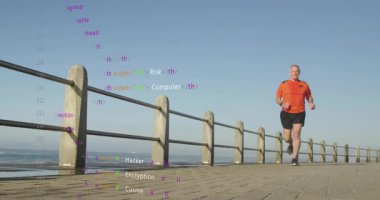 Deniz kenarında koşu yapan kıdemli bir adam, okyanus üzerinde yüzen siber güvenlik terimlerini başlatıyor. Atletik, sağlıklı, dijital, teknoloji, fitness, açık hava, sağlıklı