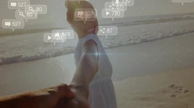 Elini tutarken, plajda dönen bir kadın sosyal medya ikonları yaratıyor ve nişanı artırıyor. Romantik, açık hava, hayat tarzı, gün batımı, bağlantı, tasasız