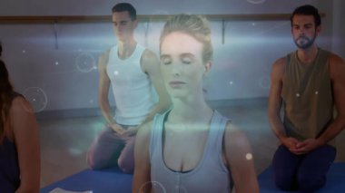 Rehberli meditasyon dersi sırasında hasırlarda diz çöküp dijital ağ örtülerini etkinleştiren bir grup. Farkındalık, sükunet, bağlantı, rahatlama, teknoloji, refah, uyum