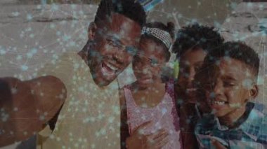 Baba akıllı telefonu uzatıyor. Aile kuruyor. Teknolojiye gülümsüyor ve animasyon örgüsüyle gülüyor. Aile, sahil, açık hava, coşku, birlik, bağlantı, mutluluk.