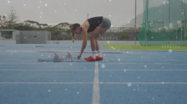 Başlangıç bloklarını taşıyan ve açıyı spor eğitimine yardım eden veri örtüsüyle ayarlayan bir atlet. Sporcu, spor, ekipman, kesinlik, teknoloji, açık hava, kararlılık