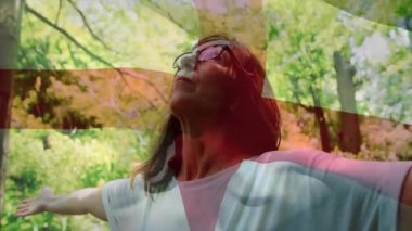 Bahçe ziyaretçisi güneş ışığıyla içeri giriyor, kollarını havaya kaldırıyor. Sağlık haçı görünümü için kollarını kaldırıyor. Doğa, sükunet, maneviyat, rahatlama, dinginlik, canlılık, açık hava.