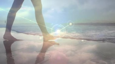 Gün batımında çıplak ayakla ıslak kuma basan bir kadın teknolojik ağ grafik izleme hareketini başlatıyor. Doğa, dinginlik, farkındalık, bağlantı, rahatlama, dijital alarm, boş zaman