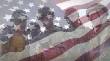 Askerler açık gökyüzü altında akıllı telefonun etrafında toplanıyor, ekrana vuruyor ve bayrak örtüsü oluşturuyorlar. Askeri, takım çalışması, dijital, vatanseverlik, taktik, iletişim, açık hava