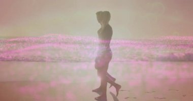 Gün batımında yürüyen kadın plajı. Önde gelen erkek, seyahat için pembe renk bozulmasına katılıyor. Siluetler, kıyı şeridi, eğlence, romantik, alacakaranlık, dinginlik, ahenk