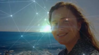 Teknisyenler güneş ışığına tepki verirken kadının gözlerini kıyı şeridine dikmesi ve kapatması. Teknoloji, bağlantı, dinginlik, içgözlem, dijital alarm, manzara, yenilik