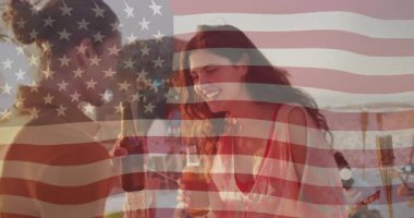 Gün batımında plaj tezgahında bira şişelerine uzanan kadın ve erkek kadeh kaldırıyor ve gülüyor. Plaj, dinlenme, dinlenme, günbatımı, arkadaşlık, kutlama, açık hava.