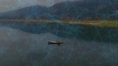 Teknoloji şebekesi senkronize olurken insan göl üzerinde süzülmek için kano ekiyor ve kürek çekiyor. Macera, keşif, dinginlik, bağlantı, teknoloji, soyutlama, manzara