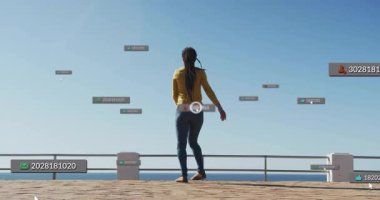 Deniz kenarındaki bir kadın yüzen teknoloji etiketleri görüyor, kolunu uzatıyor, sıçrıyor, dönüyor ve yürüyor. Kablosuz, arayüzlü, geleceksel, hareketli, yenilikçi, dijital, atletik