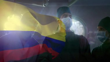 Gazlı bez teslimatı yapan forseps... Kolombiya bayrağıyla lamba altında kısırlık kontrolü yapan cerrah. Tıbbi, takım çalışması, hastane, sağlık, yenilik, profesyonellik, klinik