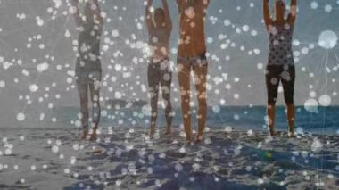 Kumsalda duran dört kadın, okyanus burunlarına karşı vücut geliştirme hareketlerini başlatıyorlar. Fitness, yoga, ahenk, açık hava, dinginlik, sağlık, farkındalık.