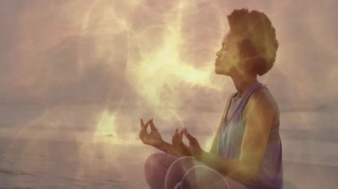 Şafak vakti, kıyı şeridinde meditasyon sırasında nefes alıp veren altın bir aura. Meditasyon, gün doğumu, dinginlik, aura, farkındalık, maneviyat, refah