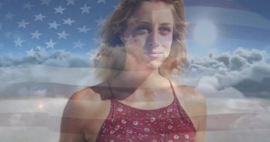 Kafasını eğen ve pazarlama için bulutların üzerinde dalgalanan Amerikan bayrağıyla gülümseyen bir kadın. Vatanseverlik, sükunet, doğa, zarafet, özgürlük, esneklik, uyum.