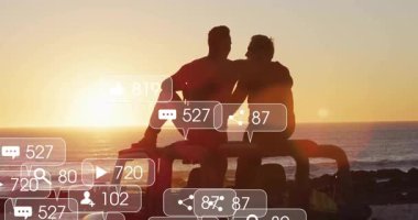 Cipin çatısına tırmanmak, okyanusun batışını izleyen iki adam, sosyal medya bildirimlerini takip etmek. Macera, arkadaşlık, sükunet, sahil, gün batımı, siluet, bağlantı