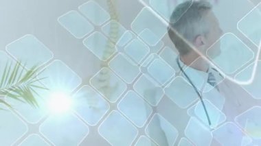 Kareler sürüklenen mercek fişekleri omurilik haritasına odaklanırken doktor başını kameraya çeviriyor. Tıbbi, sağlık, profesyonel, tanı, bilimsel, modern, sağlık