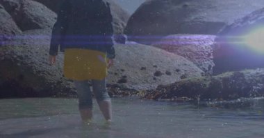 Ayaklarını sığ gel-git havuzuna sokan bir kadın, seyahat reklamı için hareketli mercek fişeği ile dalgalanan bir sahil. Kıyı, kıyı şeridi, doğa, dinginlik, boş zaman, açık hava, minimalist