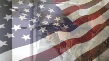 Askeri eğitim sahasında tüfeği kaldıran asker, şeffaf bayrak altında nişan alıp ateş ediyor. Askeri, eğitim, disiplin, hassasiyet, odaklanma, güç, takım çalışması